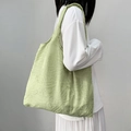 Light green tote bag with leaf jacquard texture shown on a shoulder in a casual style - Green Leaf Texture