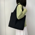 Detail of black quilted canvas tote bag with textured bubble fabric shown on shoulder - Black