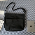 Detail of black canvas crossbody bag with dual front pockets and adjustable metal buckle strap - Black
