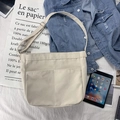 Detail of cream canvas crossbody bag with dual front pockets on denim jacket - Beige