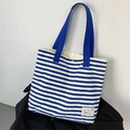 Detailansicht der gestreiften Canvas-Tasche mit Eisbären-Patch und blauen Henkeln - Blau Gestreift