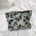 Detalle de neceser gris con mariposas bordadas y pequeña etiqueta de marca blanca - Mariposa Gris Negro