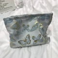 Detalle de neceser azul claro con bordado de mariposa dorada y etiqueta de tela blanca - Mariposa Azul Claro
