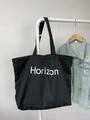 Detail einer großen schwarzen Canvas-Tragetasche mit Horizon-Aufdruck und Seitenlabel - Schwarz (Horizon-Druck)
