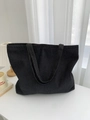 Gros plan sur la texture en denim épais et les doubles anses de ce grand sac cabas noir - Moyen / Noir