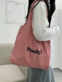 Grande borsa tote in tela a quadretti rossi con scritta Peachy indossata da una modella - Gingham Rosso (Lettera Nera)
