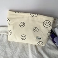 Beige corduroy makeup bag with black smiley faces and woven label on fabric surface - Beige Smiley Face Pouch