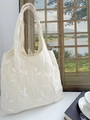 Detailed close-up of intricate white leaf embroidery on a cream lace tote bag - Embroidered Beige