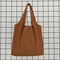Close-up of caramel canvas tote bag showing thick fabric texture and seamless handles - Brown