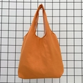 Detail of a bright orange canvas tote bag with wide shoulder straps on a grid background - Orange