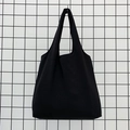 Detail of a minimalist black canvas tote bag with wide shoulder straps on a grid display - Black