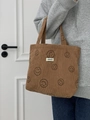 Braune Cord-Tragetasche mit Smiley-Gesicht und Webetikett, von Model gehalten - Braun