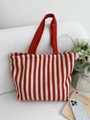 Détail du sac cabas en toile à rayures rouges et blanches posé sur un canapé - Double Couche Chevrons Rouge