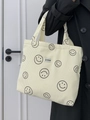 Nahaufnahme der cremefarbenen Cord-Tasche mit schwarzen Smileys und gewebtem Etikett - Cremeweiß