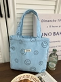 Detail of light blue corduroy tote bag featuring smiling face patterns and ATRYG label - Sky Blue