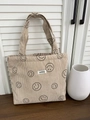 Detailaufnahme der beigen Cordstruktur und des Markenlabels auf der Smiley-Tragetasche - Khaki