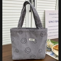 Details der grauen Cord-Einkaufstasche mit schwarzem Smiley-Druck und Logo-Patch - Grau
