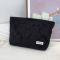 Detail of black rose embossed texture and ATRYG brand label on a fabric cosmetic bag - 3D Floral Black Makeup Bag