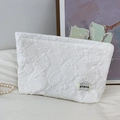 Close-up of white embossed rose texture on fabric cosmetic bag with ATRYG label - 3D Floral White Makeup Bag
