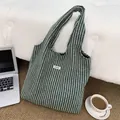 Flat lay of striped knit tote bag on rug with laptop and coffee, showing texture detail - Dark Green
