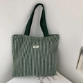 Detail of green herringbone wool tote bag featuring a stitched logo and webbing handles - Woolen Stripe Green