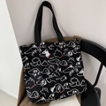 Nahaufnahme der schwarzen Segeltuchtasche mit weißen Hundemotiven und HOWL Schriftzug - Schwarzer Hundedruck