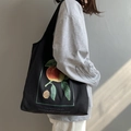 Borsa tote in tela nera con stampa di pesche e tracolla indossata da una modella - Frutto Estivo Nero Stile Gilet