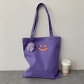 Detail van paarse canvas draagtas met oranje smiley-opdruk en pluche monsterhanger - Paars (Met Hanger)