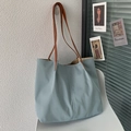 Detail view of a light blue canvas tote bag with brown straps on a white chair - No Pendant / Blue