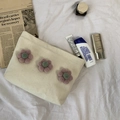 Detail der Make-up-Tasche aus Canvas mit 3D-Blumen und Hautpflege auf weißem Stoff - Blumendekoration (Beige) / Beige