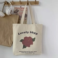 Detalle de un bolso tote de lona blanco roto con estampado floral en un gancho de madera - Beige Flor Artística Roja