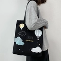 Large black canvas tote bag with colorful hot air balloon print shown on a model - Hot Air Balloon Black
