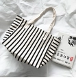Vista dettagliata della borsa tote in tela a righe su tessuto bianco con un libro - Stile Reversibile a Righe di Grande Capacità