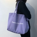 Seitenansicht der großen lila Canvas-Tasche mit 'Famous For Pizza' Aufdruck am Model - Lila