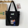 Détail du sac fourre-tout en nylon noir avec étiquettes et poche frontale zippée - Sac à Bandoulière Noir Multi-poches / Noir
