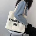 Detailansicht der bestickten Canvas-Tasche mit der Studio Clip 1949 Typografie - Bestickt Beige