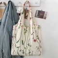 Cream canvas tote bag with elegant pink floral embroidery and vine details on white wall - Water Grass Embroidery Canvas Bag