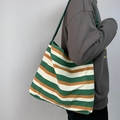 Detail of adjustable green strap and striped canvas tote bag worn by a model - Green Striped Bag (Green/White/Orange)