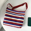 Detail of red and blue striped canvas crossbody bag with red adjustable strap on table - Red Striped Bag (Red/White/Blue)
