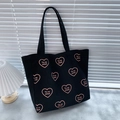 Black canvas tote bag featuring pink heart patterns and Tu es aimé French lettering - Black