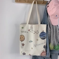Primer plano de bolsa de lona con estampado de astronauta colgada de un gancho de madera - Bolso Beige de Alien Pescando
