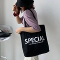 Détail du sac fourre-tout noir en toile avec imprimé Special et bandoulière large - Noir