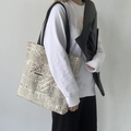 Dettaglio della borsa tote in tela con stampa di giornale indossata per la scala - Beige Giornale