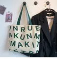 Detail of canvas tote bag with green letter print and sturdy webbing handles - KUN Green Letters