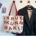 Detail of off-white canvas tote bag featuring bold red lettering and matching red handles - KUN Dark Red Letters