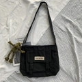 Minimalist black nylon messenger bag with a green frog keychain in a flat lay view - With Frog Pendant / Black