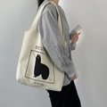 Foto lifestyle de un bolso tote de lona crema con ilustración de animales negros y texto - Estilo de Estampado de Alpaca