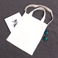 Close-up of white canvas tote bag with adjustable shoulder strap on grey background - White Dual-Use Bag with Zipper