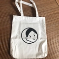 Minimalistische weiße Canvas-Tragetasche mit Linienkunst-Gesichtsdruck auf einer Webmatte - Nachdenkliche Weiße Tasche