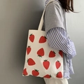 Primo piano della borsa tote in tela con stampa di fragole indossata da una modella - Fragola Fresca Ovunque (Bianco)